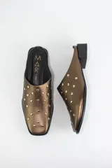 Zueco de cuero color bronce con punta almendrada y detalle de tachas metálicas doradas en toda la capellada. Posee un taco cuadrado bajo de 3 cm.