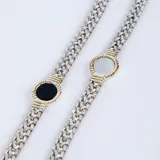 Pulsera de cadena tejida en plata con detalle central circular en oro que enmarca una piedra ónix negra.