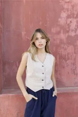 Chaleco de pana fina color beige, con escote en V, cierre frontal con botones y corte recto.