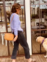 Bandolera color naranja de cuero con diseño capitoneado en forma de V.