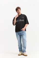 Remera negra de corte oversize, con mangas cortas amplias y cuello redondo ribeteado. Cuenta con una estampa frontal con la leyenda "Shift Mode" en tonos grises y texto secundario.