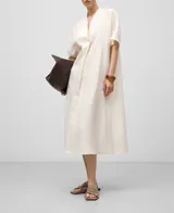 Vestido midi de lino color blanco, corte amplio, escote en pico con festón, manga corta y aberturas laterales.