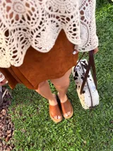 Cartera baguette de cuero color crudo con manchas negras, forro interno de tela y correa de cuero marrón.