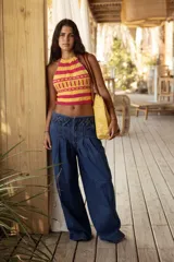 Pantalón vaquero de tiro medio con silueta wide leg y pierna amplia. Presenta una cintura trabajada con pasacintas entrelazadas, cierre frontal y bolsillos laterales. Confeccionado en denim azul.