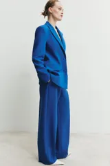 Blazer entallada de cuello solapa y manga larga con hombreras. Presenta bolsillos con solapa en el delantero, forro interior a contraste y cierre frontal con botones forrados.
