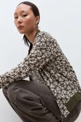 Campera bomber verde oliva con estampado geométrico en blanco, cuello, puños y cintura elásticos.