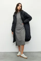 Campera de nylon larga oversized color negro, con capucha, tres bolsillos externos y uno interno. De tela capitoneada, con puños en las mangas y forro polar.