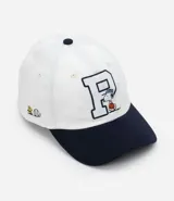 Gorra blanca de sarga con visera azul marino y bordado de Snoopy jugando baseball.