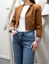 Blazer crop color marrón, marca Dictionary. Cuello con solapa, manga larga y forro interno estampado a rayas.