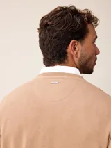 Sweater de punto con cuello en V, manga larga y puños acanalados. Presenta un pequeño logo bordado en el pecho.