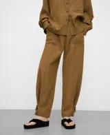 Pantalón de visco-poliamida color verde, efecto arrugado, con bolsillos frontales, costuras cargadas, cintura elástica en la espalda y bajo ajustable con trabilla y botón.