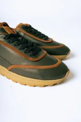 Championes de cuero en combinación de colores verde oliva y detalles en cuero color suela. Presentan cordones al tono y una suela de goma robusta en color suela con diseño dentado.