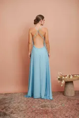 Vestido largo de gasa color celeste, con escote en V profundo y tirantes finos. Presenta una falda larga con gran caída y movimiento.