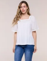Blusa blanca de corte holgado, confeccionada en modal y algodón, con escote cuadrado y mangas cortas amplias adornadas con detalles de puntilla calada.