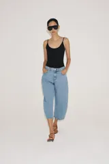 Jeans capri balloon leg de tiro medio en color celeste, con trabillas para cinto, bolsillos delanteros y traseros, y cierre frontal con botón y cremallera.