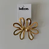 Par de aros con forma de flor, uno plateado y otro dorado.