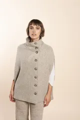 Capa color beige con textura de espiga, cuello alto con botones y aberturas laterales para los brazos. Confeccionada en lana fina sin teñir.
