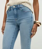 Pantalón bootcut de tiro alto confeccionado en jean de algodón con elastano. Presenta trabillas en la cintura, cierre frontal con botón, bolsillos clásicos con bolsillo reloj y bajo acampanado.