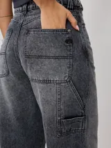Jean de corte baggy y tiro medio, confeccionado en denim de algodón en tono azul claro con efecto lavado. Presenta diseño de cinco bolsillos, cierre frontal con botón y cremallera, y pernera ancha.