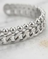 Set de dos pulseras de acero plateado, una compuesta por eslabones tipo cadena gruesa y otra por pequeñas esferas unidas.