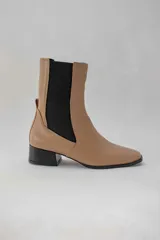 Botas de cuero color beige con elásticos laterales negros, taco cuadrado y punta cuadrada.