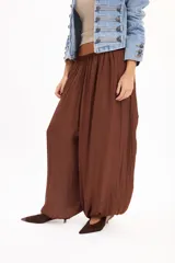 Pantalón marrón fluido de corte ancho y relajado, con cintura elástica fruncida y diseño abombado en las piernas.
