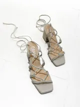 Sandalias de tacón color beige con tiras finas que se atan al tobillo y punta cuadrada.