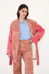 Kimono de jean con estampado tipo bandana en tonos rojizos y anaranjados, con forro interior de corderito blanco. Presenta un diseño de corte recto, mangas largas y cinturón del mismo tejido.