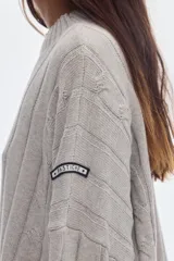 Buzo negro de tejido de ochos, con cuello redondo y diseño oversized de corte largo y amplio con tajos laterales.