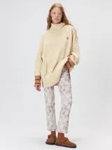 Pullover de punto color rojo, con cuello tortuga, corte holgado y mangas largas con puños acanalados en contraste con rayas blancas. Presenta un logo bordado en el pecho.