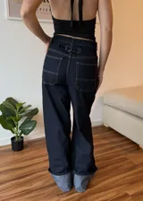 Pantalon de jean azul oscuro con costuras en contraste, corte wide leg y ruedo con doblez ancho en tono denim claro.
