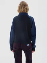 Buzo de friza suave color azul marino, con cuello polo y cartera de botones en contraste azul denim. Mangas raglán con franjas laterales azules y logo bordado en el pecho.