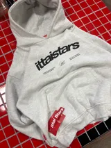 Hoodie gris jaspeado con capucha, bolsillo frontal tipo canguro y estampado gráfico en el pecho con la marca ittaistars.