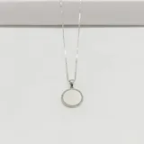 Conjunto de cadena y dije plateados. El dije es una medalla redonda con borde de pequeñas circonias y centro liso.