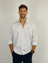 Camisa de manga larga con estampado de rayas verticales finas en color azul sobre fondo blanco. Presenta cuello clásico, cierre frontal con botones y logo bordado en el pecho.