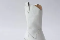 Botas de estilo western (texanas) de caña media, color blanco, confeccionadas en cuero. Presentan bordados decorativos en la caña y puntera cuadrada. Cuentan con cierre lateral y taco de altura media.