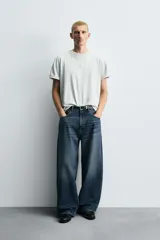 Jeans de denim de algodón, color azul oscuro con efecto lavado. Presentan un corte muy holgado (baggy fit) en toda la pierna y tiro medio. Tienen cinco bolsillos y cierre frontal con cremallera y botón.