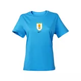 Remera deportiva Nike de mujer, color celeste, con cuello redondo y manga corta. Lleva el escudo de la Asociación Uruguaya de Fútbol (AUF) con cuatro estrellas bordadas arriba y el logo de Nike en el pecho.