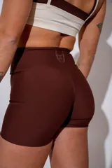 Calza corta deportiva de tiro alto en color marrón, confeccionada en tejido elástico con ajuste ceñido al cuerpo.