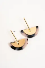 Aros colgantes compuestos por una pieza semicircular de resina con patrón carey en tonos grises y blancos, combinada con un aplique metálico dorado de diseño geométrico.