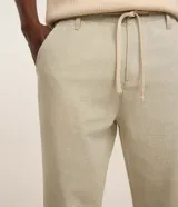 Pantalón masculino relaxed fit confeccionado en oxford de algodón, color beige, con trabillas en la cintura y cordón ajustable con lazo. Cuenta con bolsillos delanteros y traseros.