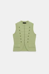 Chaleco de punto en color verde claro, con cuello redondo y diseño sin mangas. Presenta un estilo militar con detalles de alamares, botones decorativos dorados en el frente y bolsillos falsos con tapeta. Cierre frontal con corchetes ocultos.