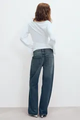 Jeans de tiro medio con corte relajado y diseño de cinco bolsillos. Presenta trabillas en la cintura, cierre frontal con cremallera y botón metálico, con un acabado de lavado desgastado.