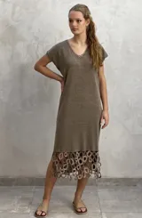 Vestido midi de tejido de punto color marrón, con cuello en V y mangas cortas. Presenta un diseño holgado y un detalle decorativo de crochet con formas circulares en el ruedo.