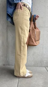 Pantalón de jean color beige, de corte recto y tiro alto, con bolsillos delanteros y traseros.