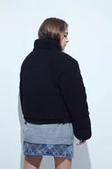 Campera puffer de corderito negro con cuello alto y diseño oversized. Presenta una textura tipo teddy, cierre frontal y corte a la cintura.