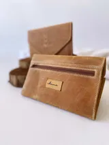 Billetera tipo sobre confeccionada en cuero color camel, con solapa en punta y detalle de costura decorativa en forma de espiga. Cuenta con cierre de broche y monedero externo.