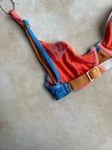Top de bikini con aro, diseño de bloques de color en tonos azul, naranja y crema, con breteles regulables y cierre metálico en la espalda.