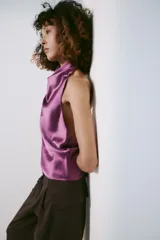 Top halter confeccionado en tejido satinado de color lila, con escote fluido y hombros descubiertos. Presenta cierre en la espalda con botón oculto.