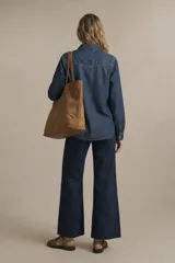 Camisa de jean azul oscuro, de corte ajustado, con cuello clásico, botones frontales, dos bolsillos con solapa en el pecho y mangas largas con puños abotonados.